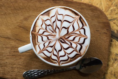 棕色和白色咖啡与花卉艺术在白色陶瓷杯 · 免费素材图片