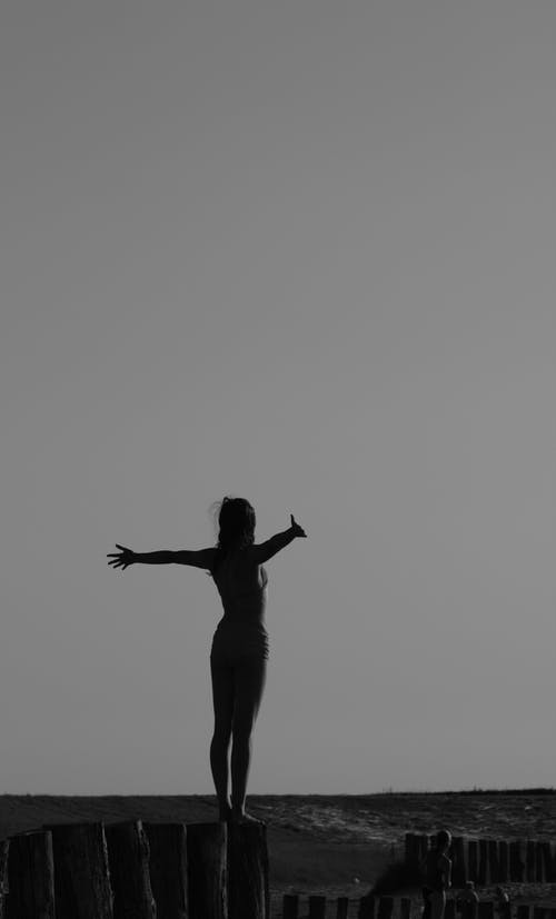女人站在日志上的灰度照片 · 免费素材图片