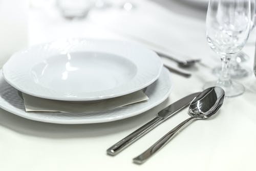圆形白色陶瓷碗放在酒杯旁边的桌子上 · 免费素材图片