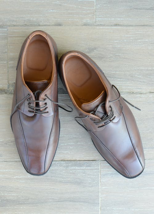 一双棕色皮革礼服鞋放在灰色的表面上 · 免费素材图片