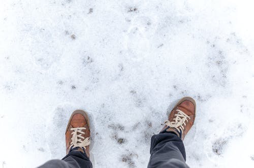 穿棕色的低帮运动鞋，站在冰雪覆盖的地板上的人 · 免费素材图片