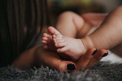 选择性聚焦摄影中握住婴儿脚的人 · 免费素材图片