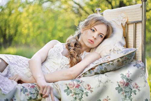 躺在蓝色和白色的花卉床单上的女人 · 免费素材图片