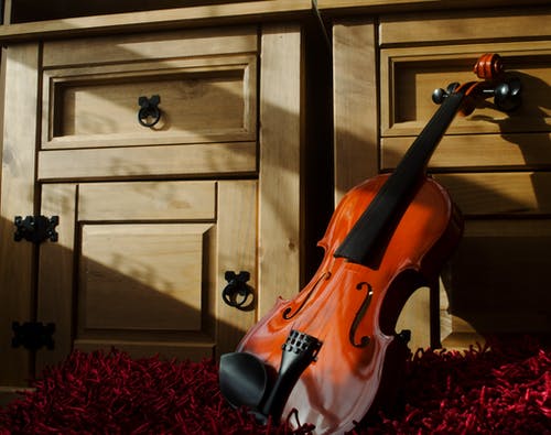 棕色小提琴倚在棕色木柜 · 免费素材图片