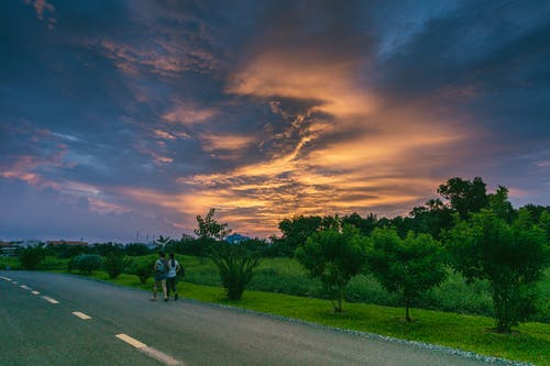 两人在草地旁边的道路上行走 · 免费素材图片