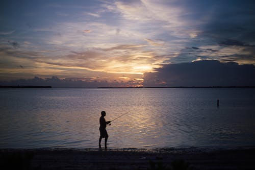 男子站在海岸线上的轮廓 · 免费素材图片