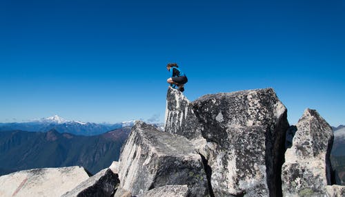 身穿蓝色和白色衬衫站在悬崖上的人 · 免费素材图片