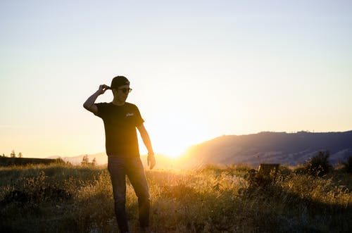 男子站在草地上，俯瞰日出 · 免费素材图片