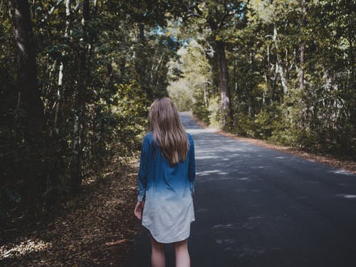 女人穿着蓝色和白色的长袖衬衫，走在树附近 · 免费素材图片