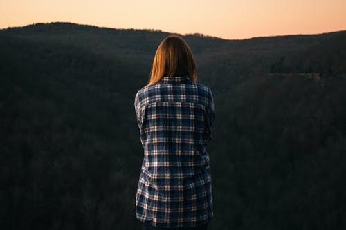 在绿色的山峰前穿蓝色和白色的格子衬衫的女人 · 免费素材图片