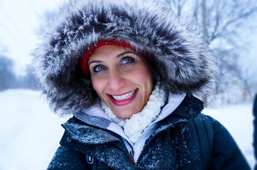 关闭在雪季穿黑色拉链大衣外套的女人的照片 · 免费素材图片