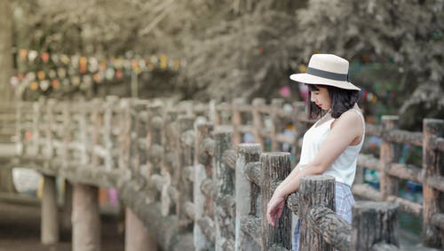 女人穿着白色背心和白色帽子站在木板上 · 免费素材图片