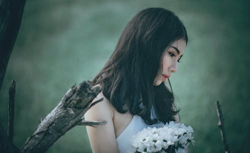 俯视时拿着白色花瓣的花束的白上衣的女人 · 免费素材图片