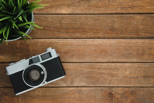 棕色木质表面上的黑色和银色胶卷相机 · 免费素材图片