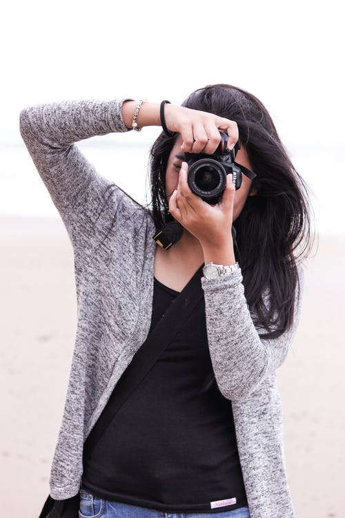 灰色羊毛衫和黑色衬衫，拿着黑色的单反相机的女人 · 免费素材图片