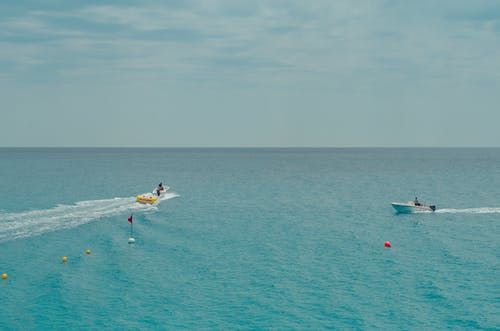 两人在湛蓝的天空下的水体上骑乘船只 · 免费素材图片