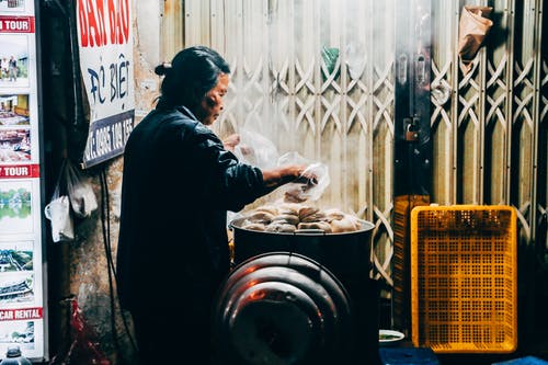 一个女人在灰色的长袖上衣，拿着塑料袋的照片 · 免费素材图片