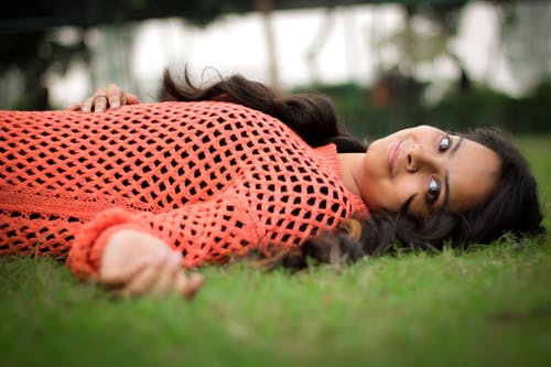 躺在草坪上的橙色长袖衬衫的照片女人 · 免费素材图片