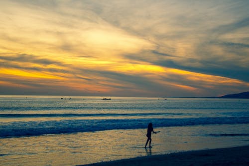 在海滩海岸上行走的人的照片 · 免费素材图片