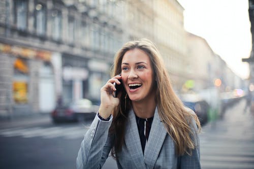 金发女人穿着灰色西装外套拿着智能手机 · 免费素材图片