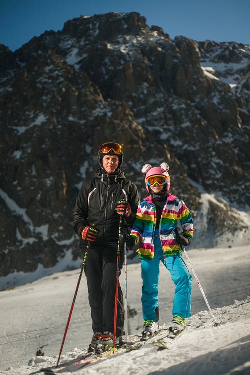 男人和女人在下雪时穿雪滑雪服和两极滑雪 · 免费素材图片