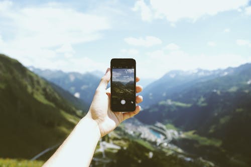 持有太空灰色iphone 5s的人拍照山 · 免费素材图片