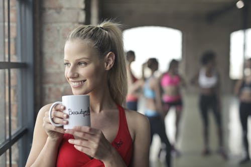 女人穿着红色的背心，拿着白色的陶瓷杯 · 免费素材图片