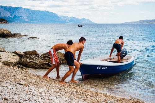 三名男子在海边推快艇 · 免费素材图片