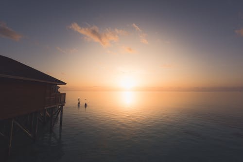 人的剪影摄影在水体与日落背景 · 免费素材图片