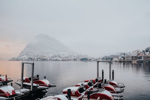 白色和红色的小船，在白雪山附近的码头上 · 免费素材图片