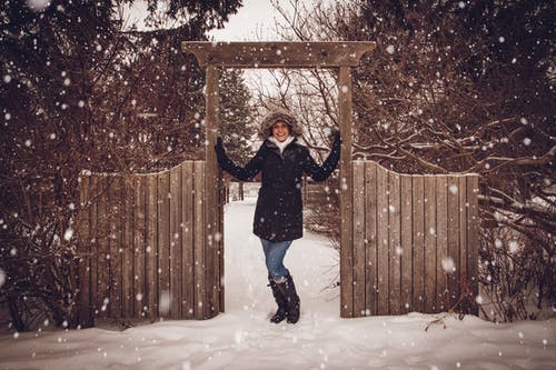 黑色外套在栅栏旁边在雪中的女人 · 免费素材图片