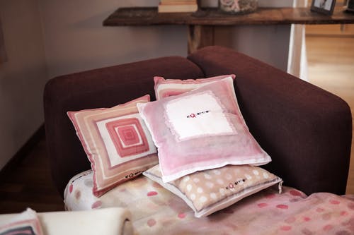 在软垫红色沙发上的四个什锦颜色枕头 · 免费素材图片