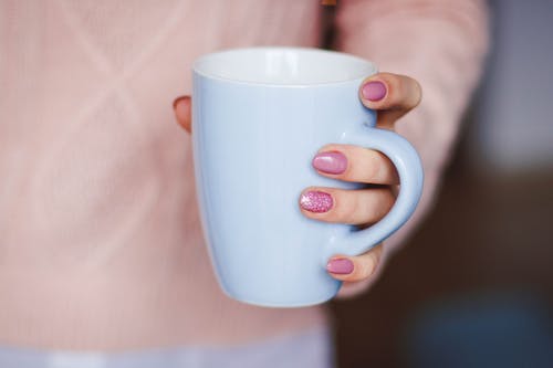 拿着白色陶瓷杯的人 · 免费素材图片