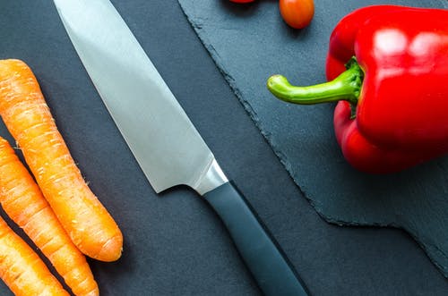 黑色处理灰色厨房刀旁边橙色胡萝卜和红色bellpepper · 免费素材图片