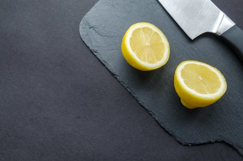 在黑色表面上的刀旁边切柠檬 · 免费素材图片