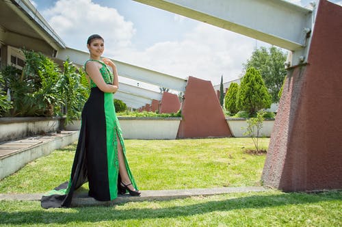 站在墙前的绿色和黑色礼服的女人 · 免费素材图片