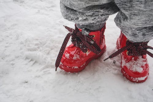 蹒跚学步穿红鞋站在雪地上 · 免费素材图片