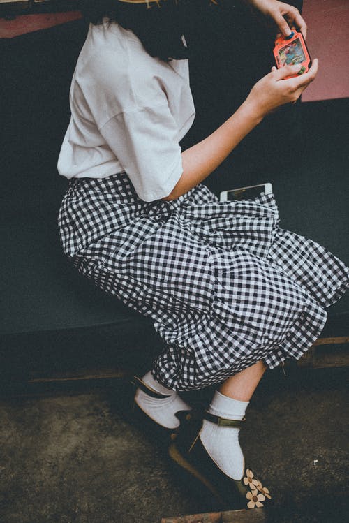 女孩坐在沙发上玩便携式控制台的特写照片 · 免费素材图片