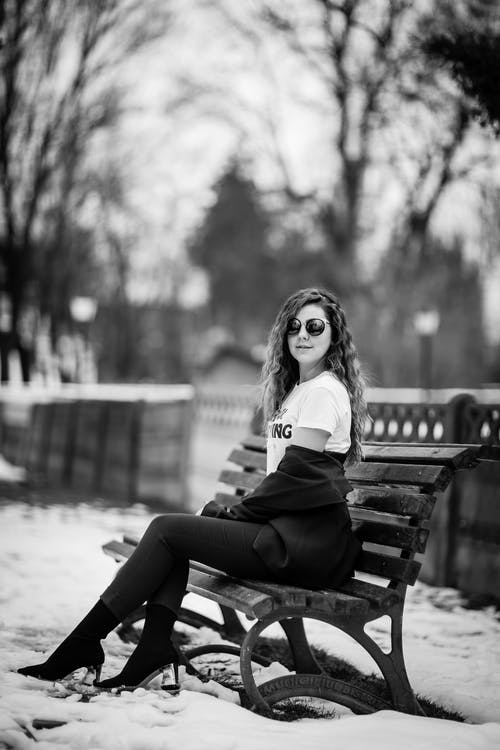 女人坐在长椅上的灰度摄影 · 免费素材图片