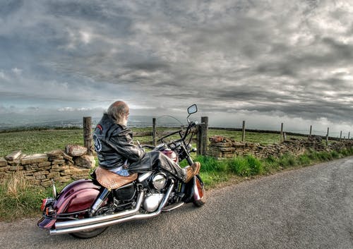 在道路上穿黑色皮夹克骑巡洋舰摩托车的人 · 免费素材图片