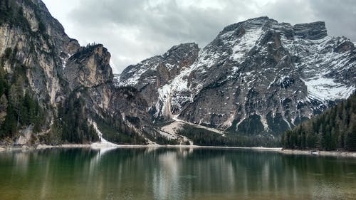 灰色多云的天空下的雪山 · 免费素材图片