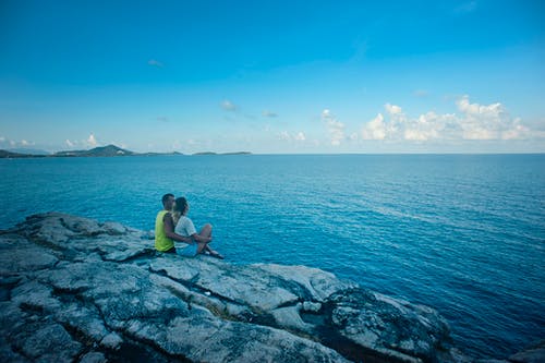 男人和女人坐在水体附近 · 免费素材图片