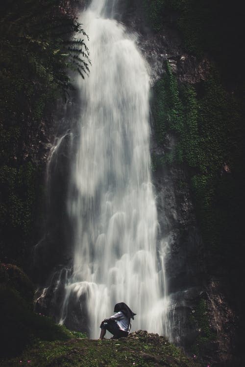 坐在瀑布附近的人的照片 · 免费素材图片