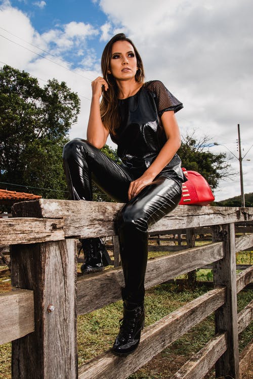 在农场坐在栅栏上穿黑色西装的女人 · 免费素材图片
