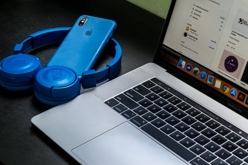 Macbook Pro旁边蓝色无线耳机 · 免费素材图片