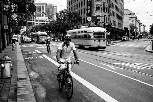人在街上骑自行车的灰度照片 · 免费素材图片