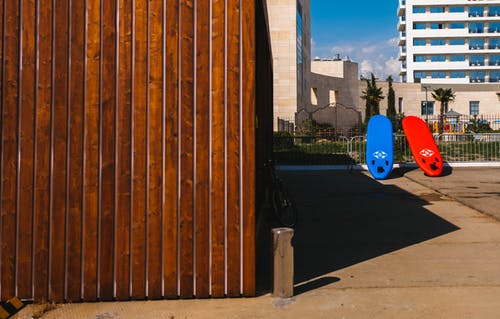 棕色木屋附近的红色和蓝色冲浪板 · 免费素材图片