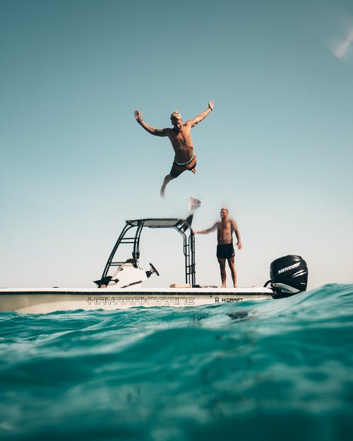 男子从船上跳到大海的照片 · 免费素材图片
