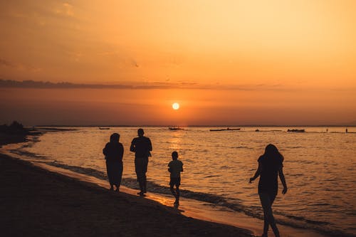 在日落期间在海边散步的人的剪影 · 免费素材图片