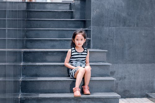 黑色和白色的条纹的裙子，坐在楼梯上的女孩 · 免费素材图片